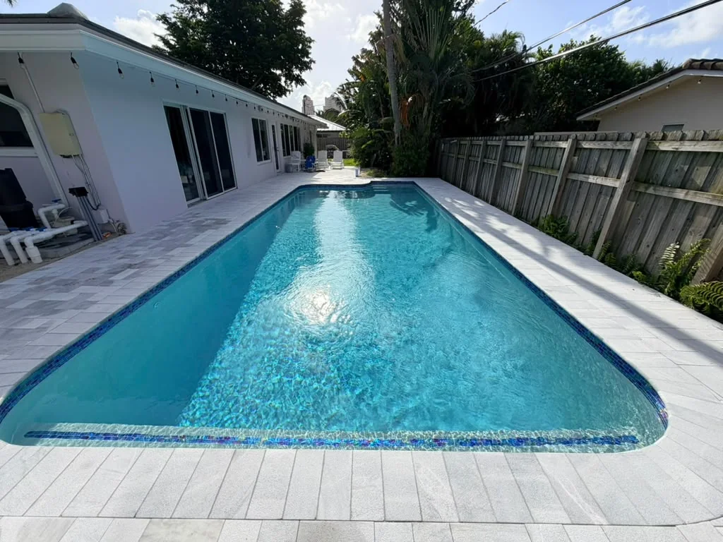 Renovated backyard pool with a white marble paver deck